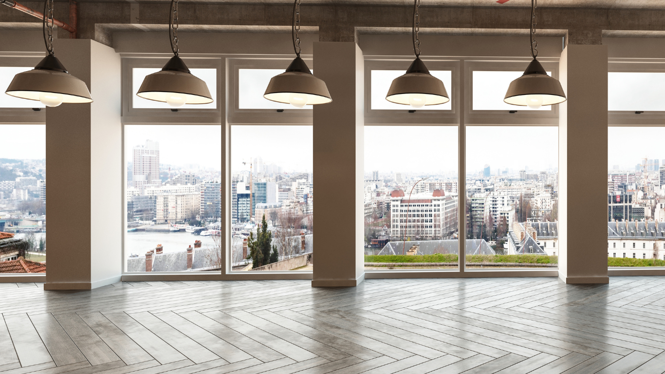 Modern empty room with city view through large windows; pendant lights.