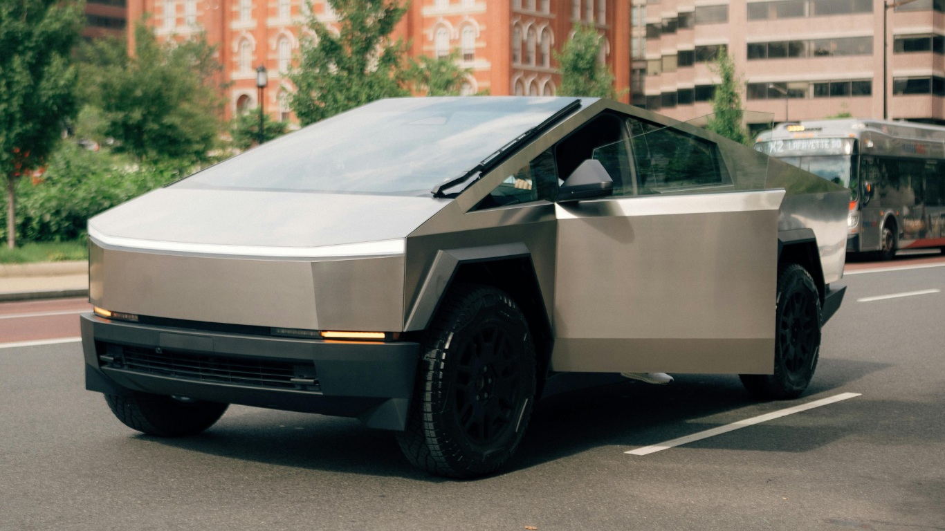 A tesla cybertruck is driving down a city street with its doors open. tesla wall connector