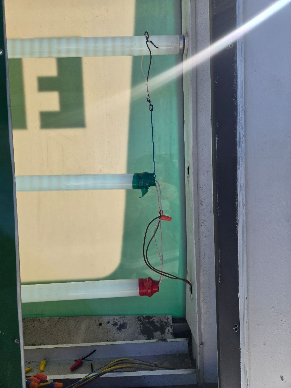 Man in a brown hoodie and cap installing a ceiling fan in a room.