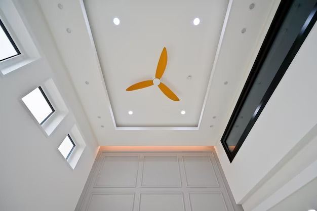 A bright white room with an ornate ceiling and a yellow ceiling fan.