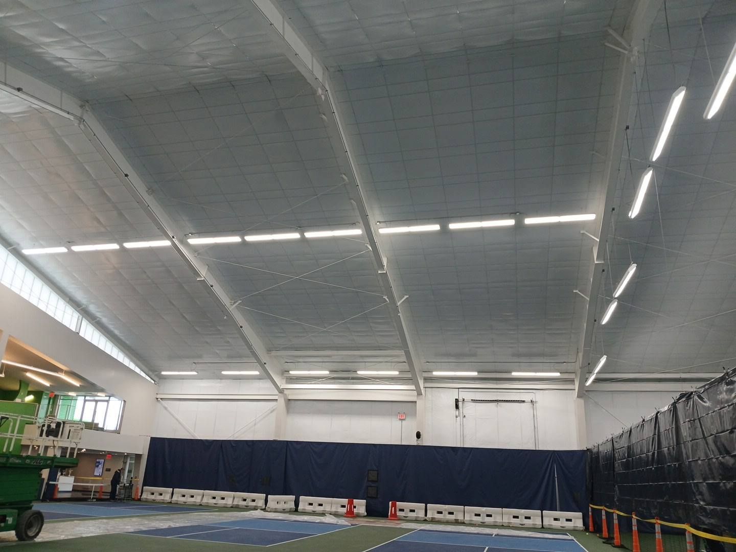 A person with blue hair and a hard hat is working on an air conditioning unit outside.