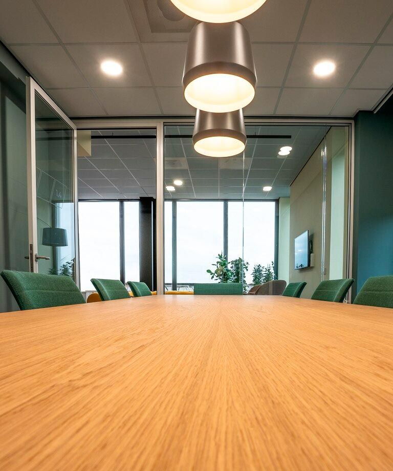 A conference room with a long wooden table and green chairs - commercial electrician