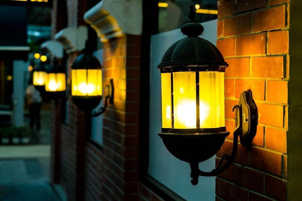 Lanterns illuminate a brick wall, creating a warm glow in an outdoor setting.