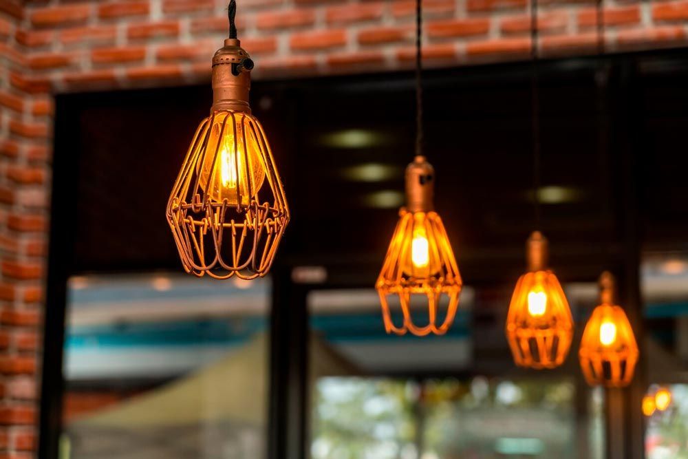 A row of light bulbs hanging from the ceiling in front of a brick wall.