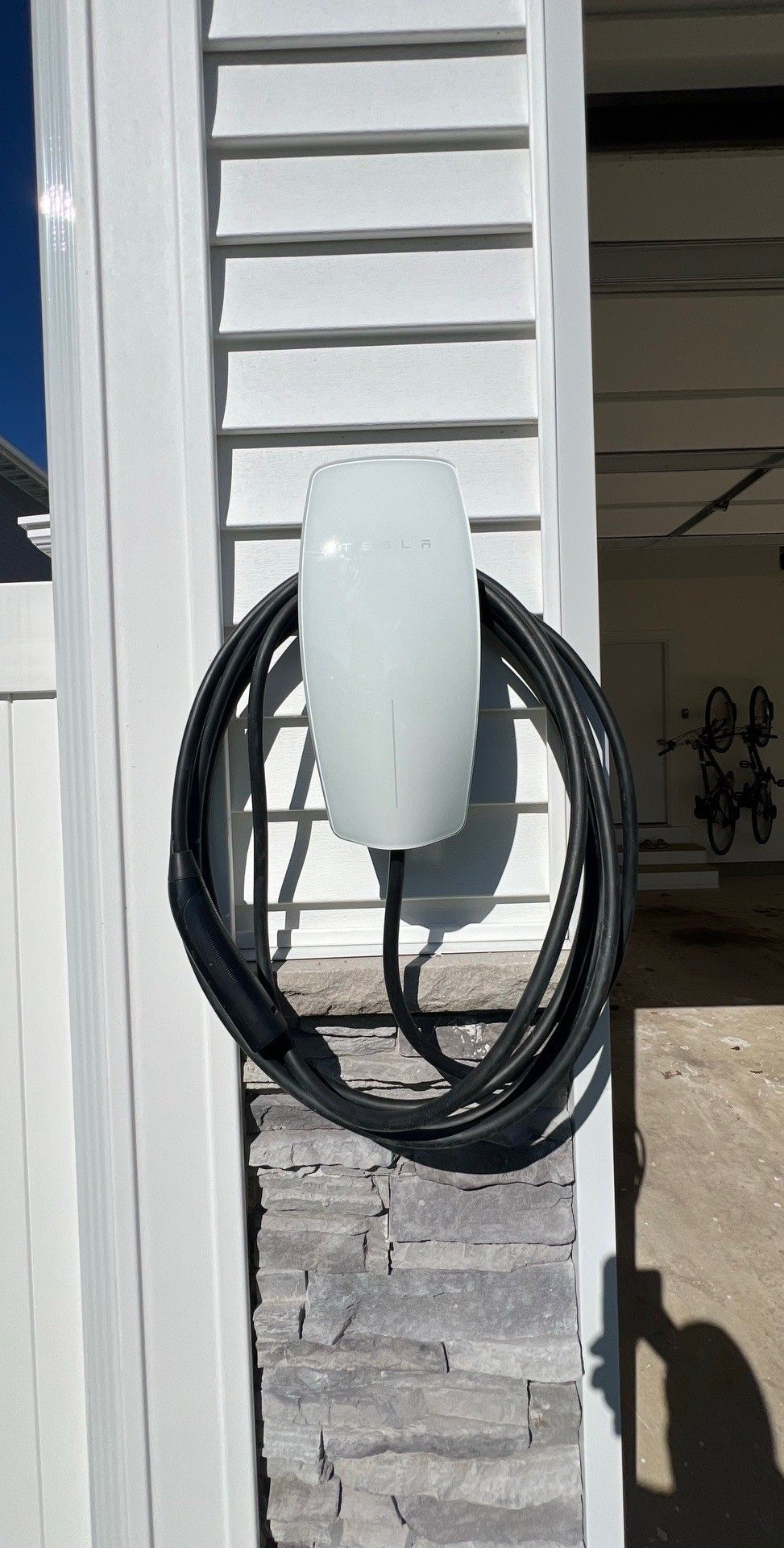 Electric car charging; charging cable plugged into the car's port, taillight visible.