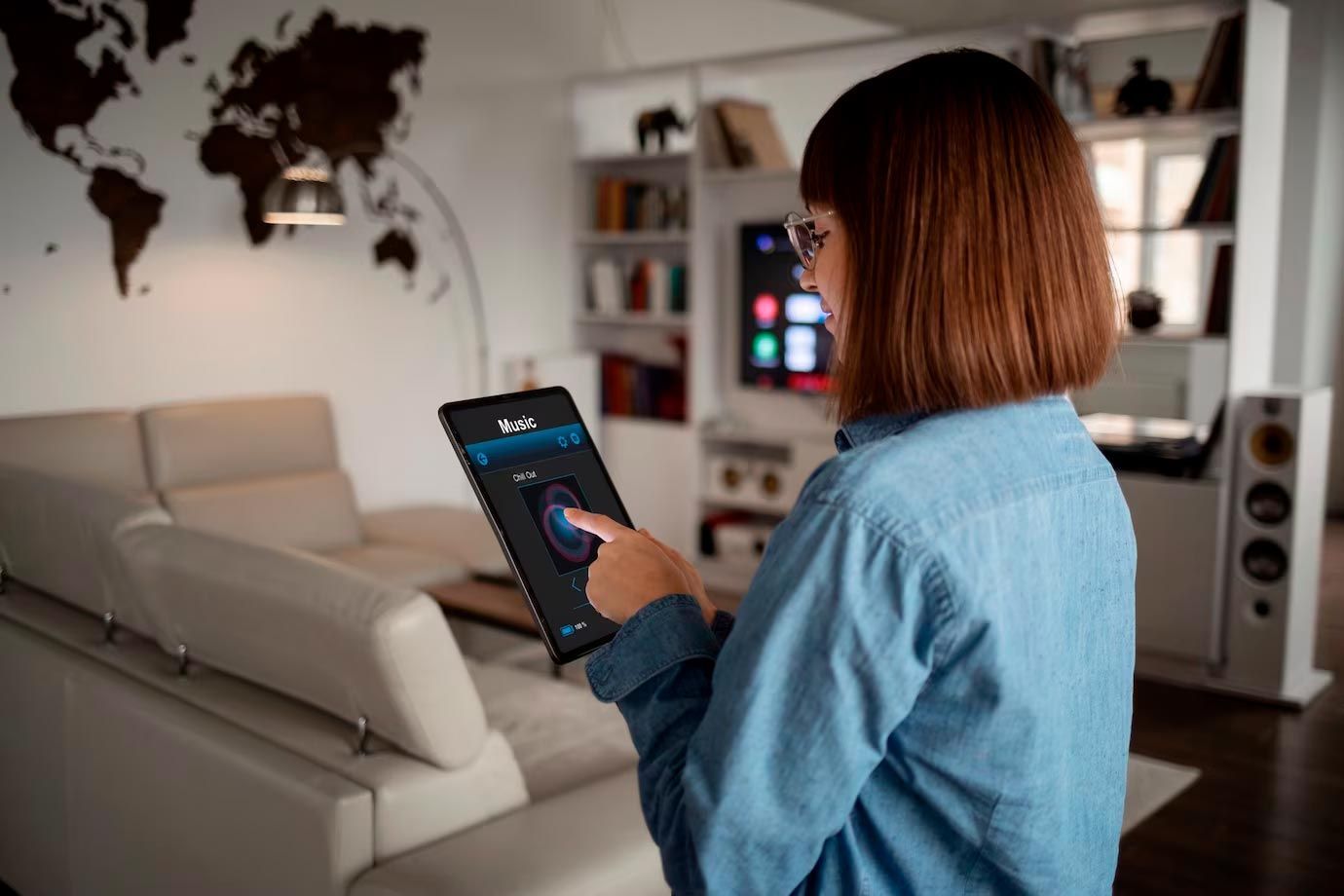 Woman using a tablet in a modern living room, adjusting a smart home device.