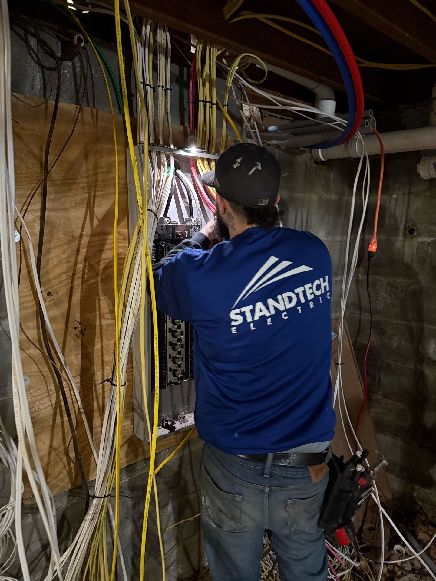 Two construction workers shaking hands in front of a power pylon, one smiling, wearing a hard hat and safety vest.