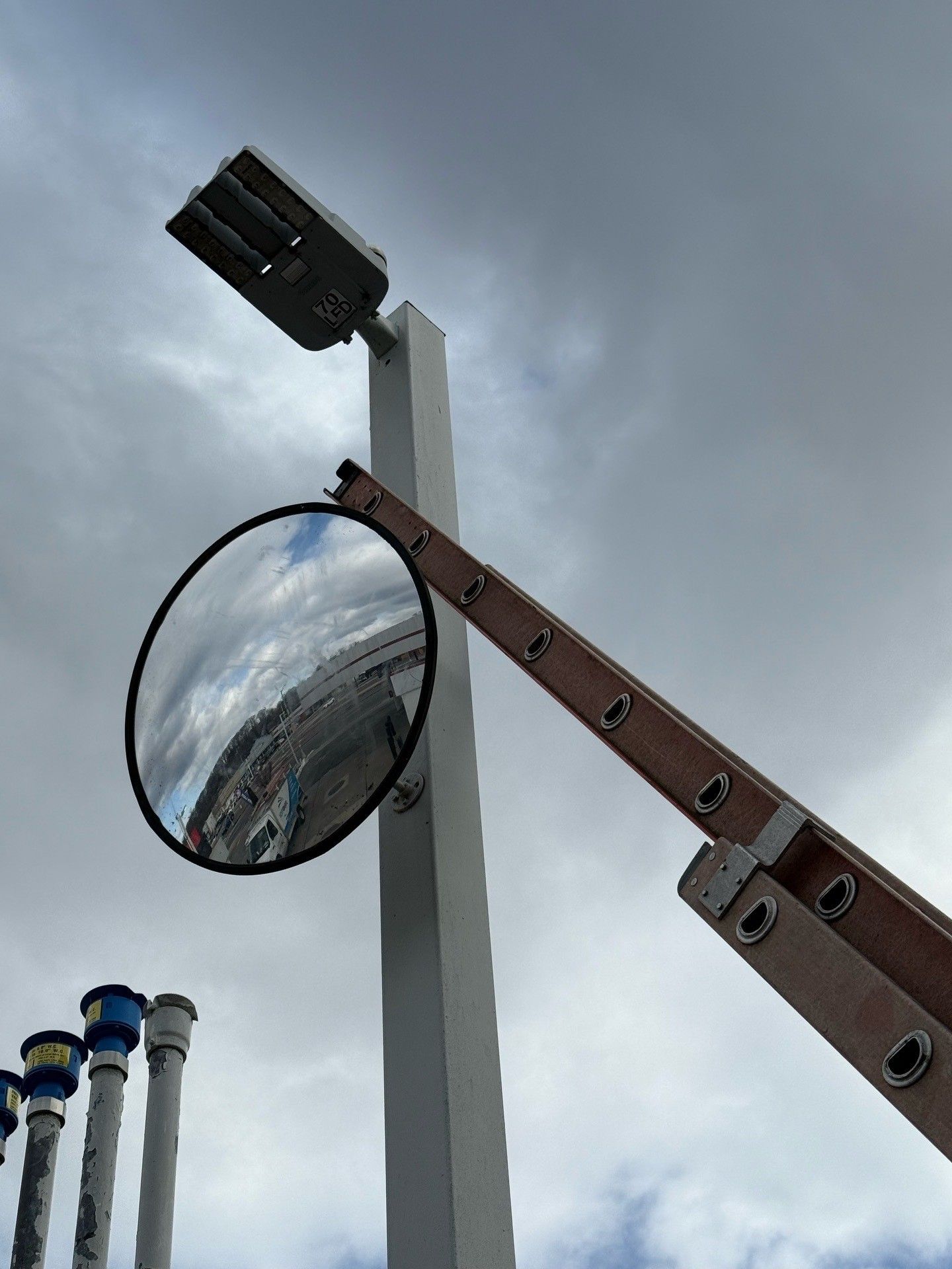 Man in a brown hoodie and cap installing a ceiling fan in a room.