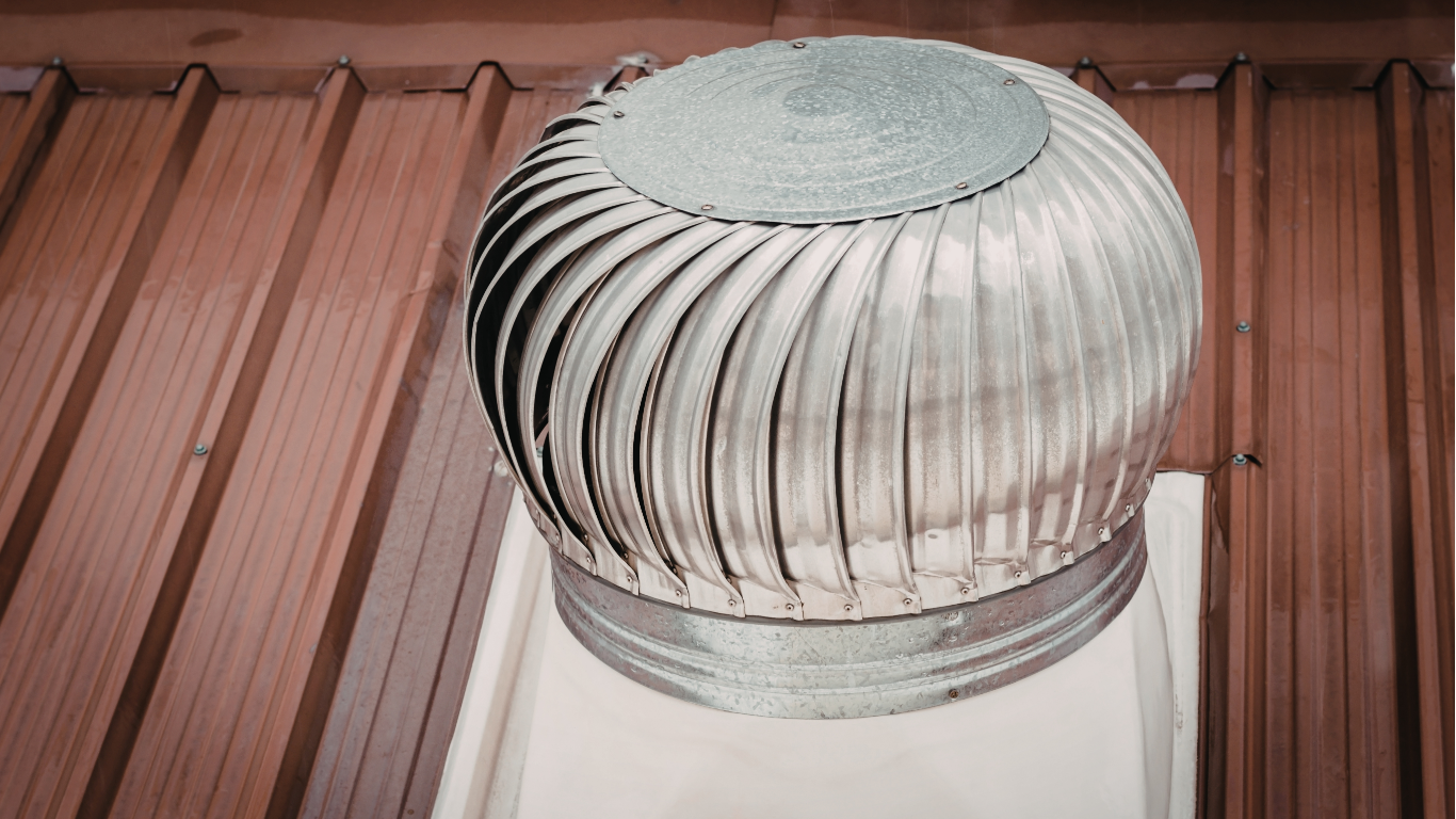 A metal wind turbine roof vent mounted on a brown corrugated metal roof.