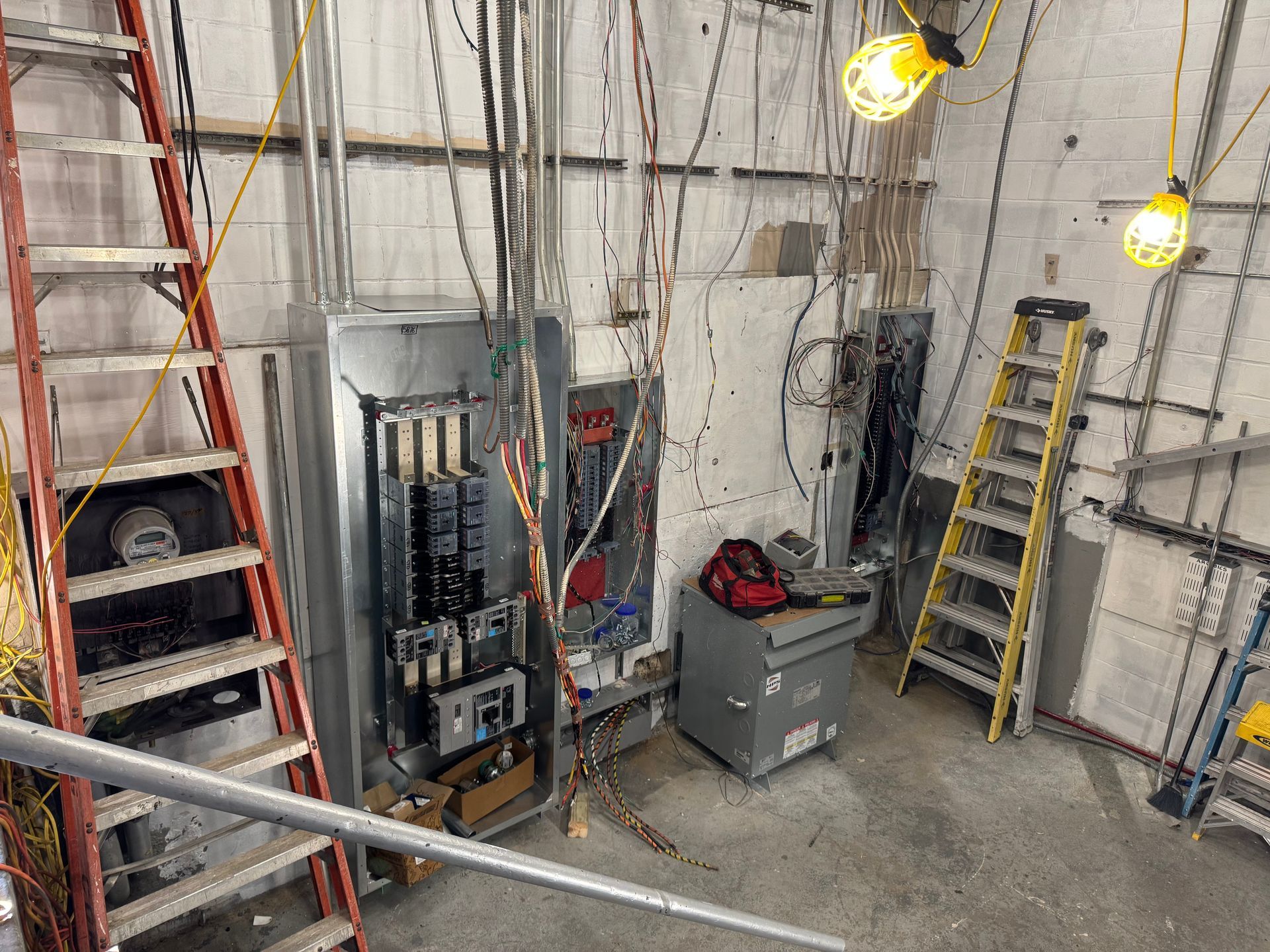 Man in a brown hoodie and cap installing a ceiling fan in a room.