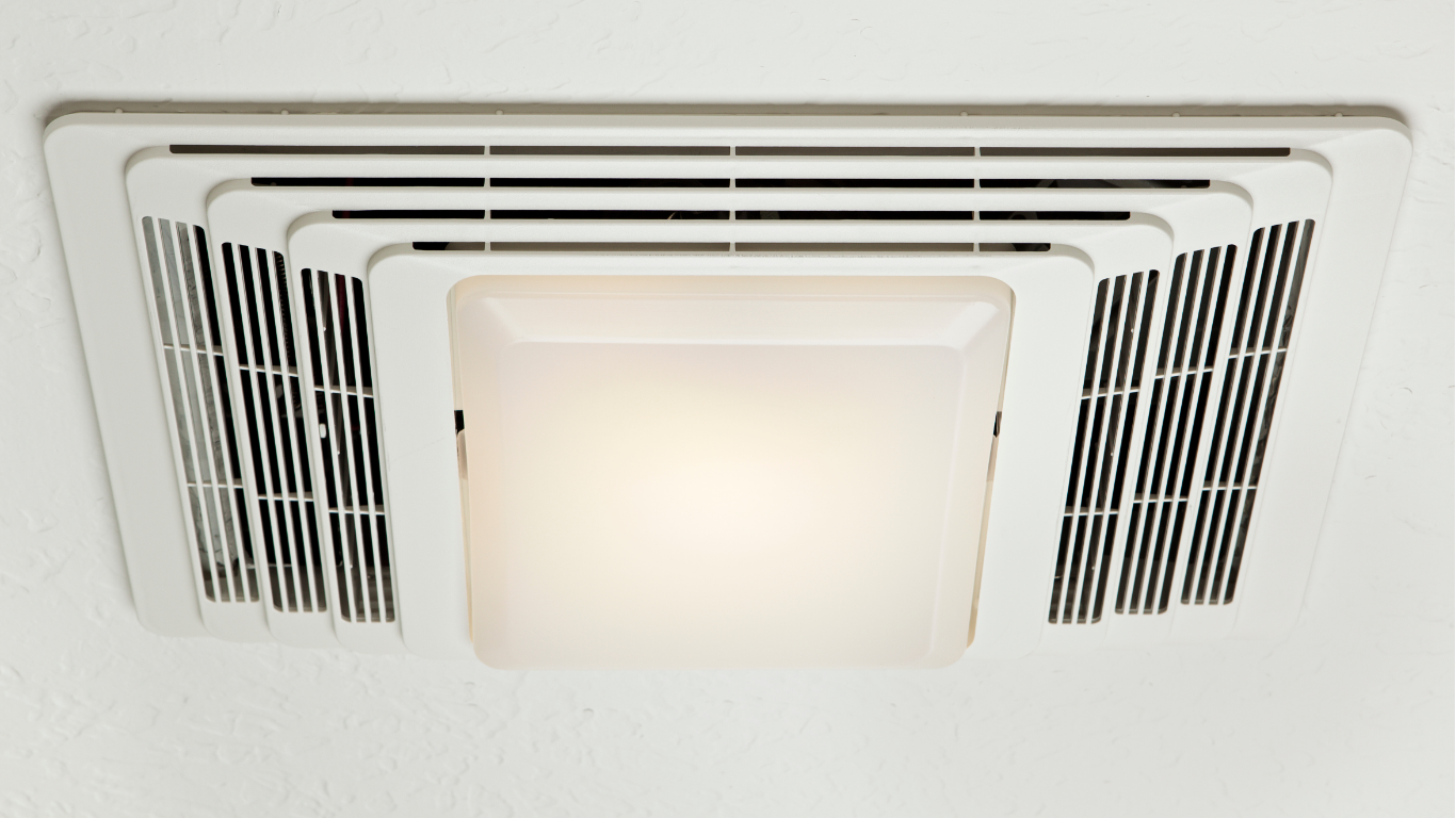 A white bathroom ceiling exhaust fan with a central square light fixture installed in a white ceiling.
