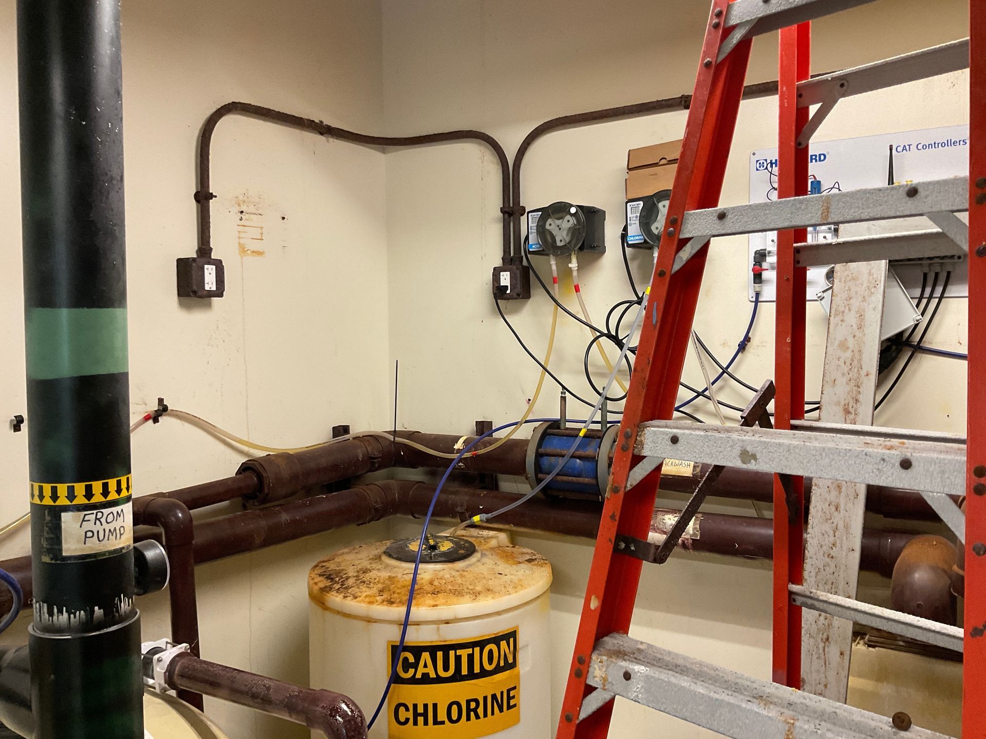 Man in a brown hoodie and cap installing a ceiling fan in a room.