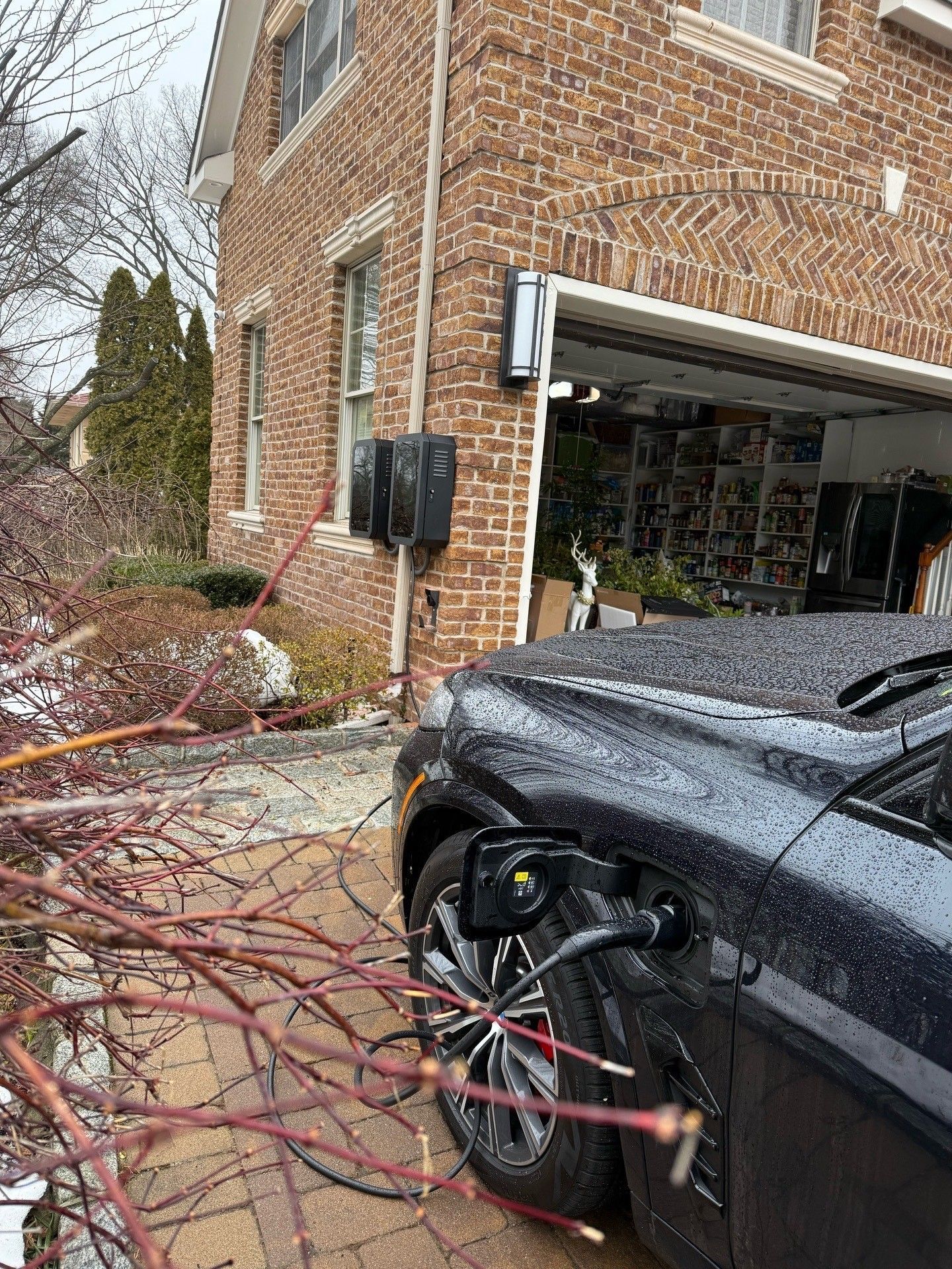 Electrician using a multimeter to install an EV charger on a white wall.