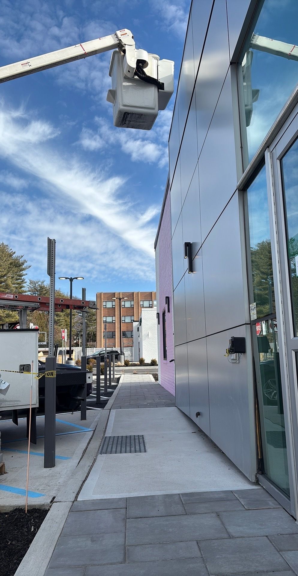 Man in a brown hoodie and cap installing a ceiling fan in a room.
