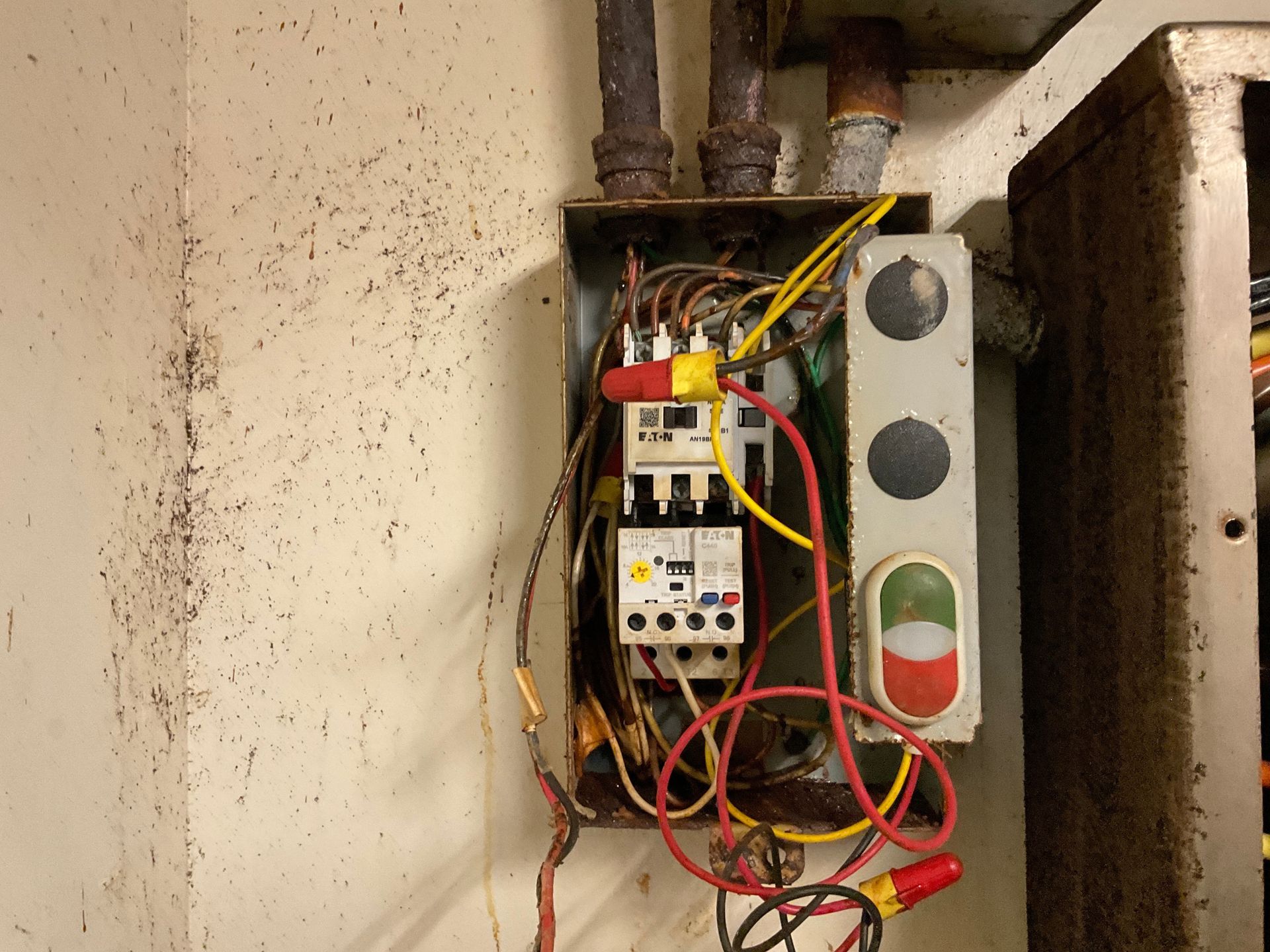 Man in red shirt installing a ceiling fan in a room with a white ceiling.