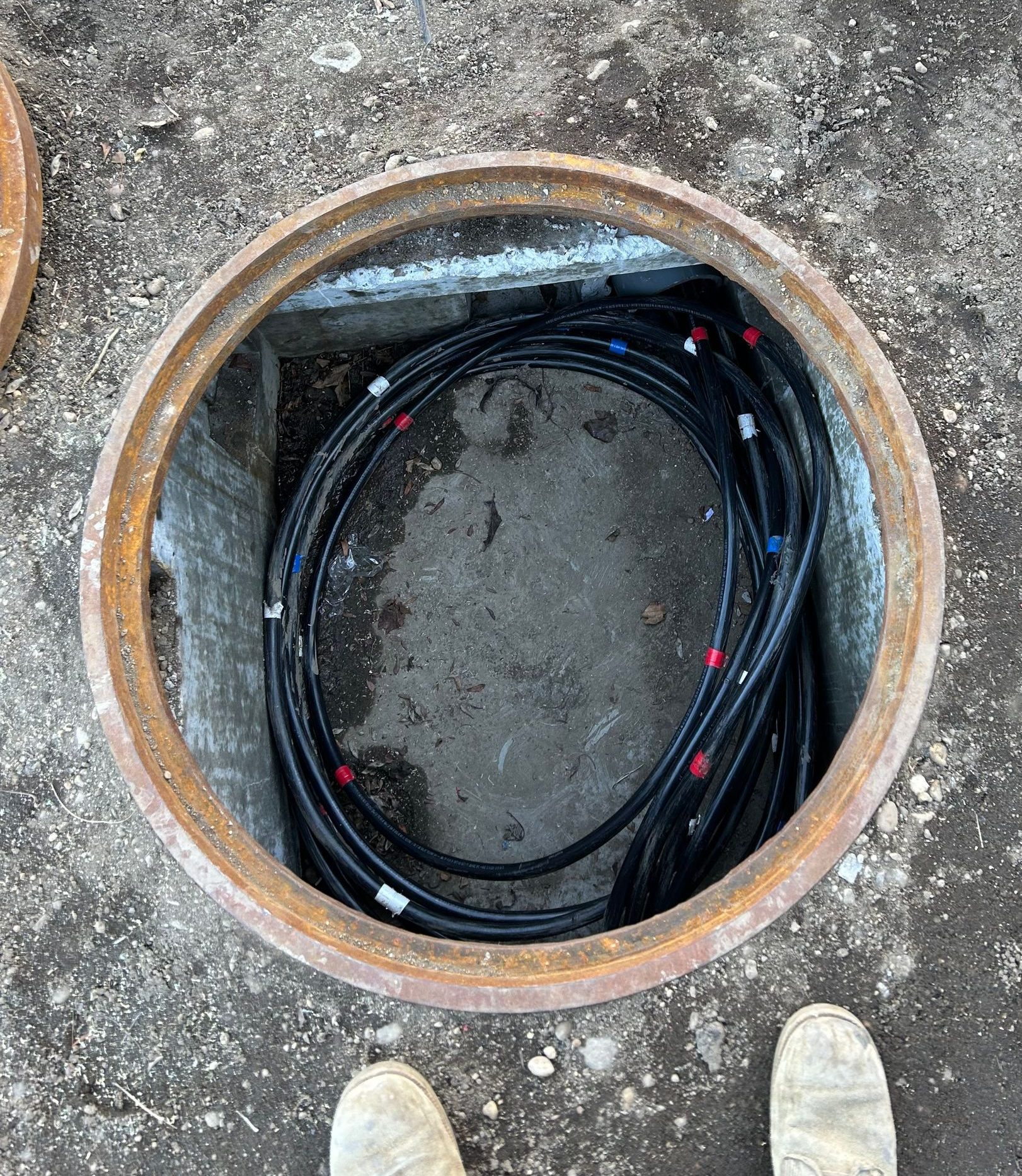 Man in a brown hoodie and cap installing a ceiling fan in a room.