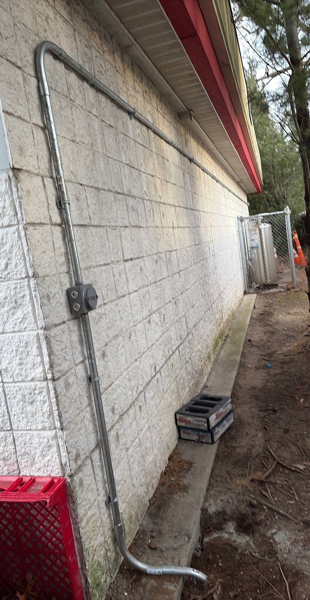Man in red shirt installing a ceiling fan in a room with a white ceiling.