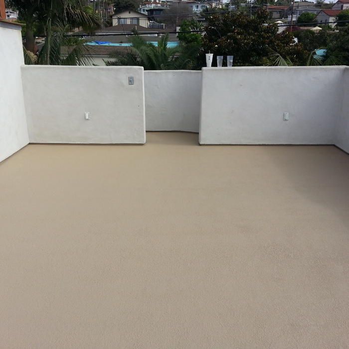 Tan-colored rooftop with white walls, overlooking a residential area with trees.