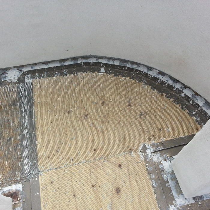 Plywood flooring with curved metal edging, concrete-colored walls.