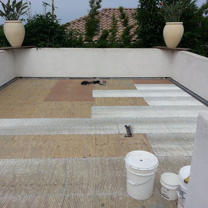 A partially tiled rooftop with white, tan, and brown tiles, several buckets, and two decorative pots.