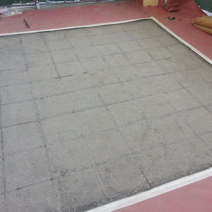 Sand-filled rectangular frame on a red surface, marked with grid lines.