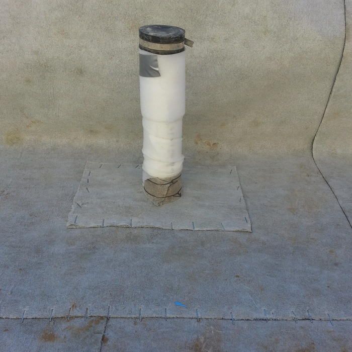 White pipe vent secured on a flat roof.