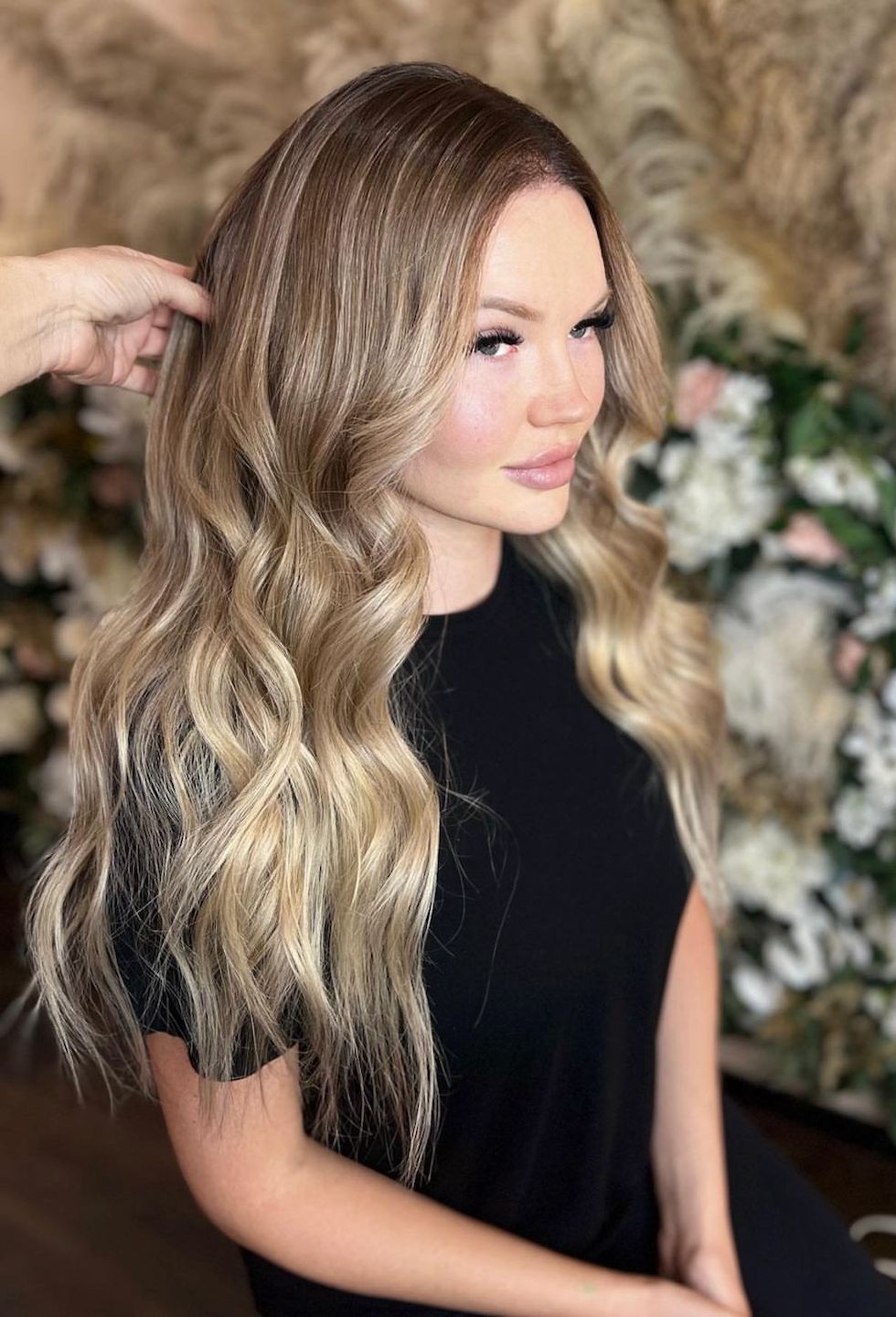 A woman with long blonde hair is getting her hair done in a salon.