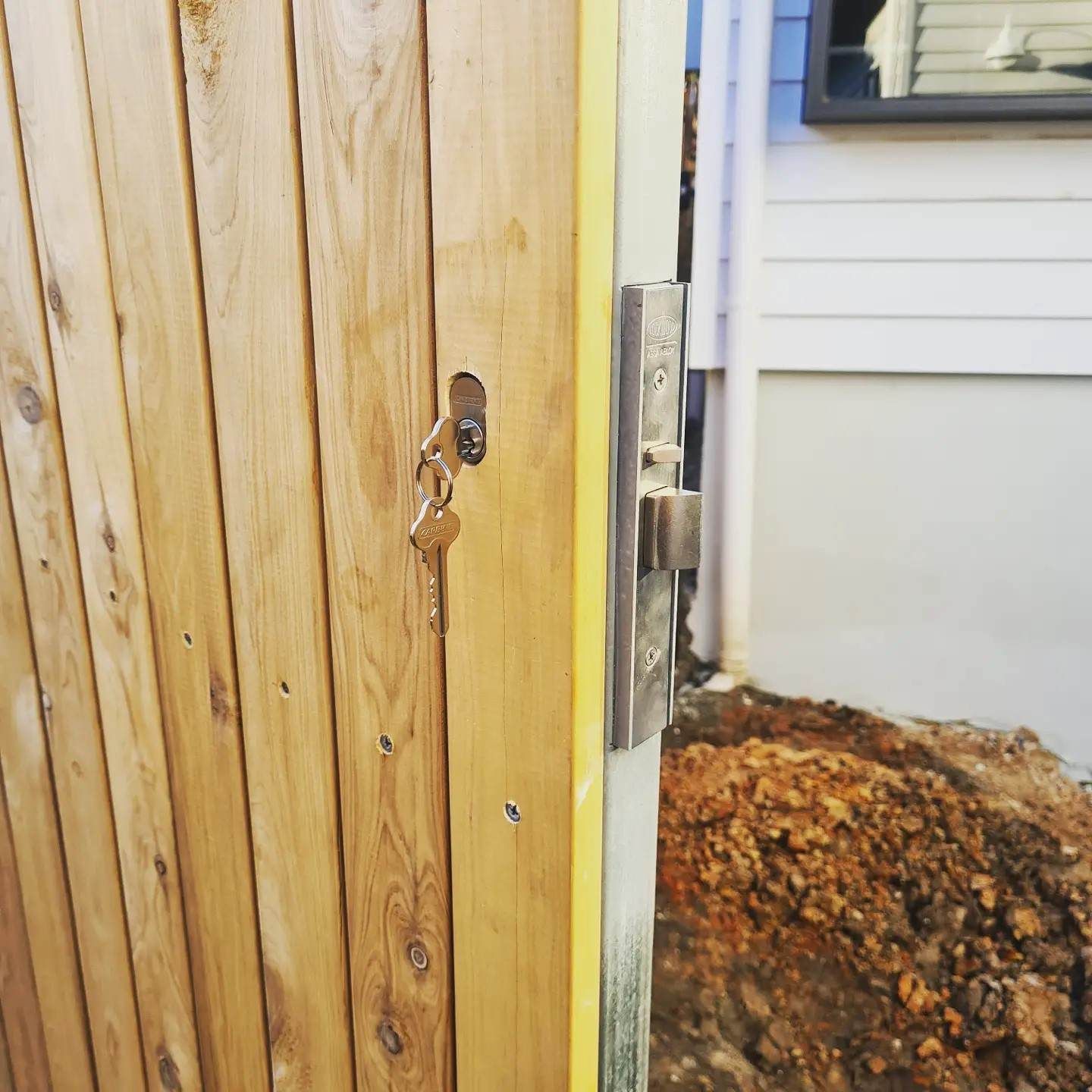 A Wooden Fence With A Key In The Lock — Barwon Locksmith & Security Doors in Grovedale, VIC