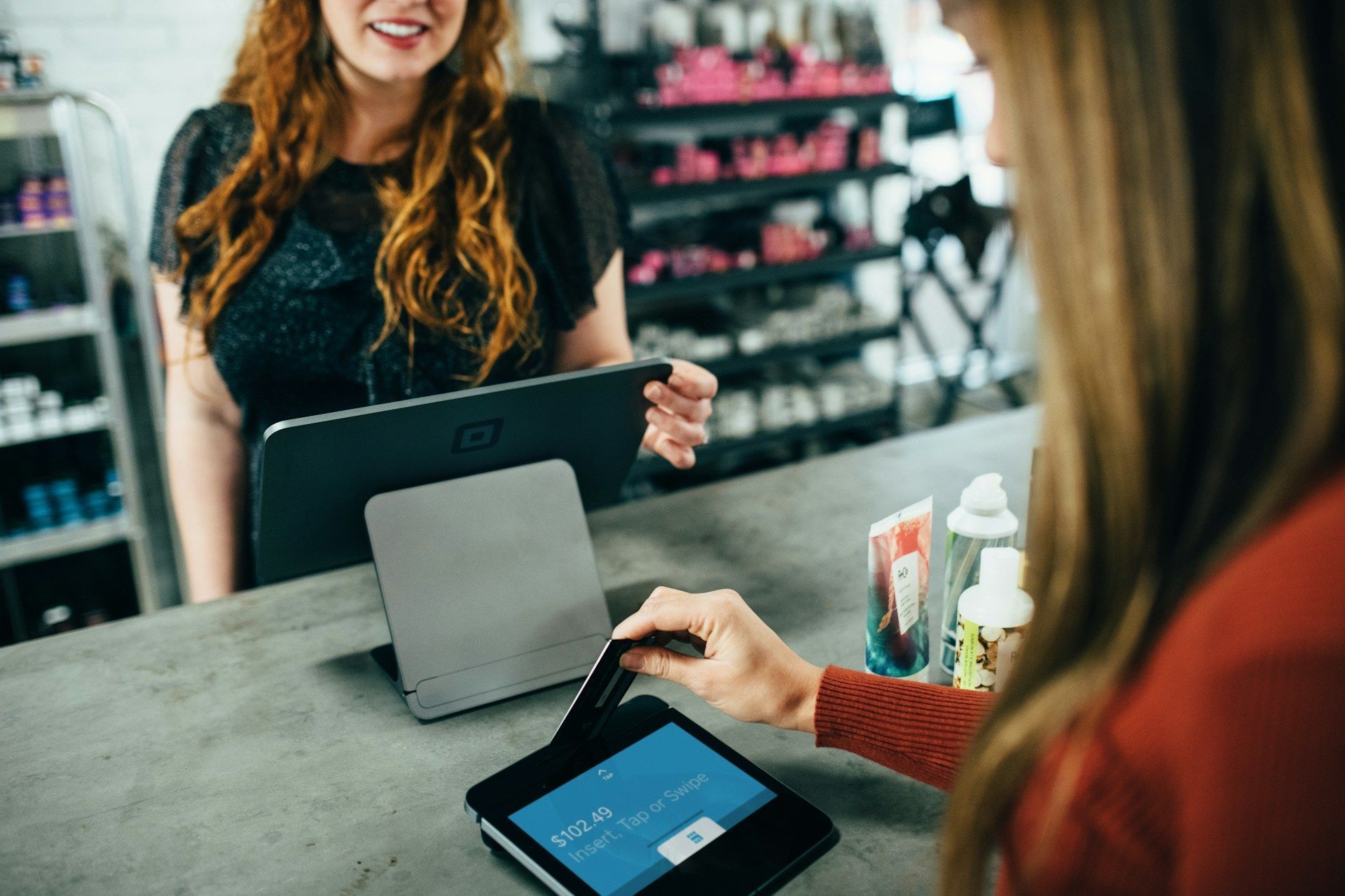 A woman is using a tablet to pay for something in a store.