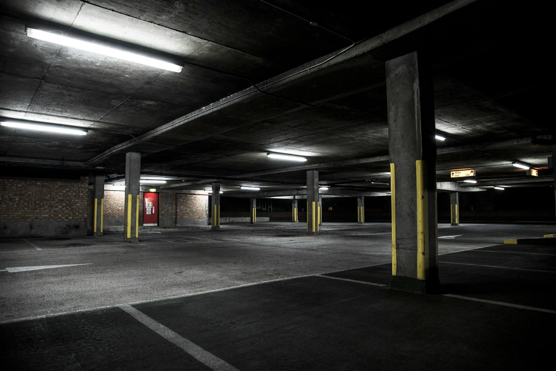 An empty parking garage with a fire extinguisher on the wall.