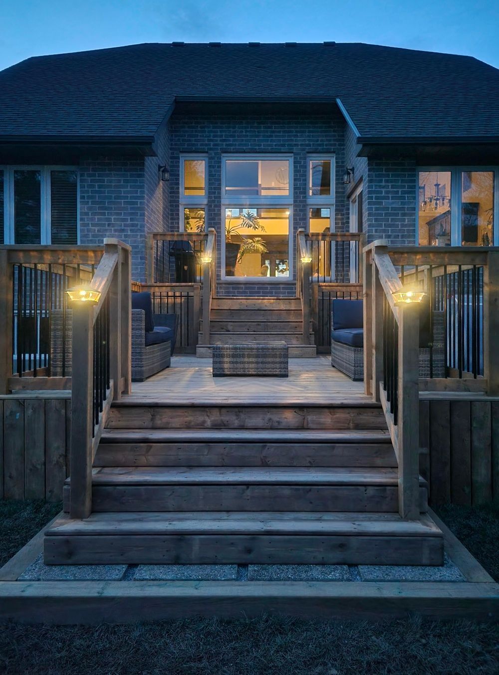The back of a house with a wooden deck and stairs at night.