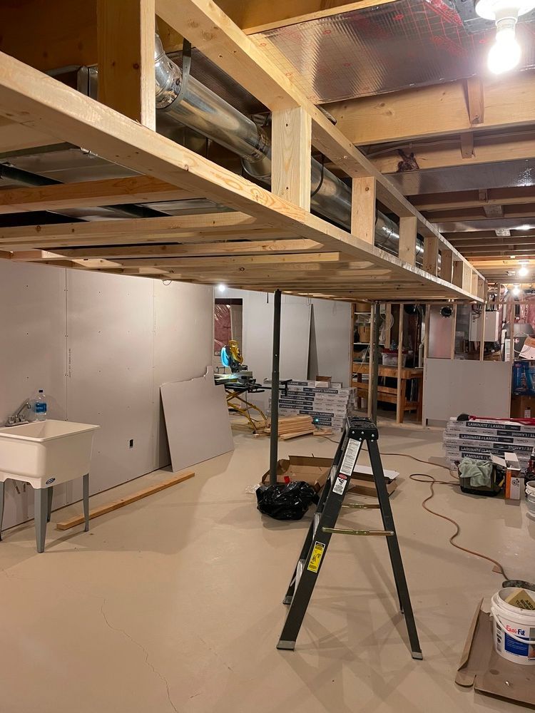 A ladder is sitting in a basement under construction.