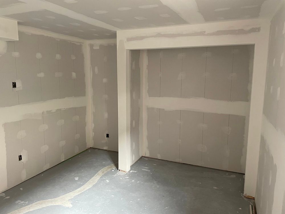 A room with drywall walls and a gray floor.