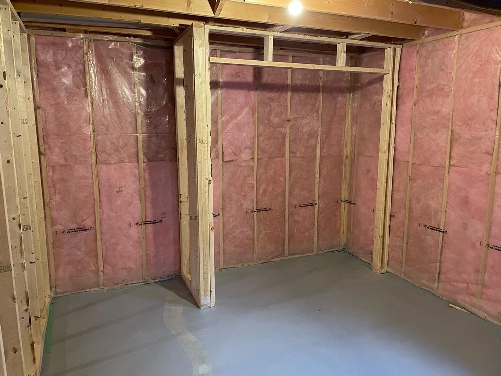 A room with pink insulation on the walls and a gray floor.