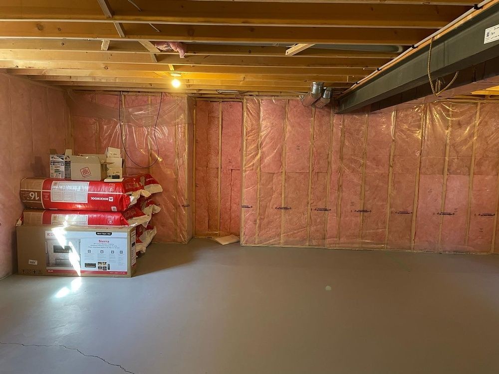 A basement with pink insulation and boxes stacked on top of each other.