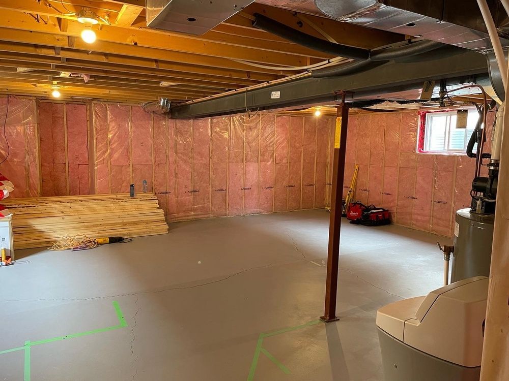An empty basement with pink insulation on the walls and ceiling.
