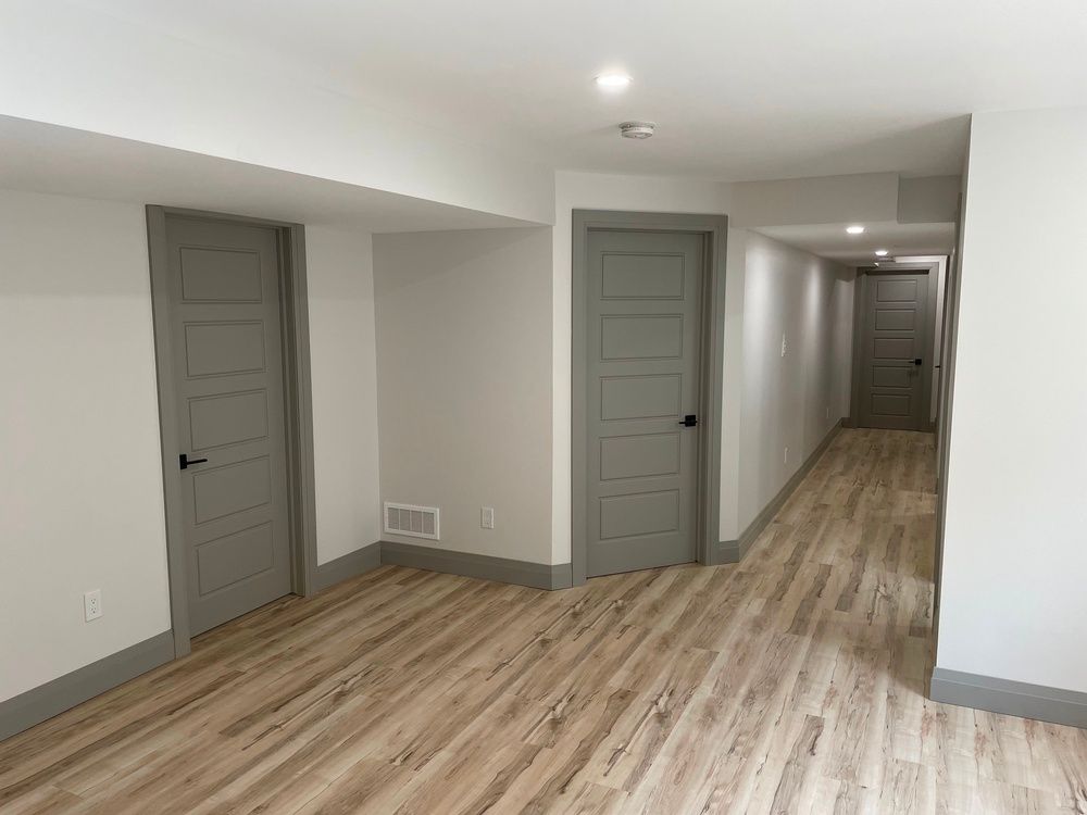 A long hallway with wooden floors and gray doors.