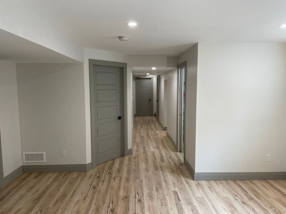 An empty hallway with wooden floors and gray doors in a house.
