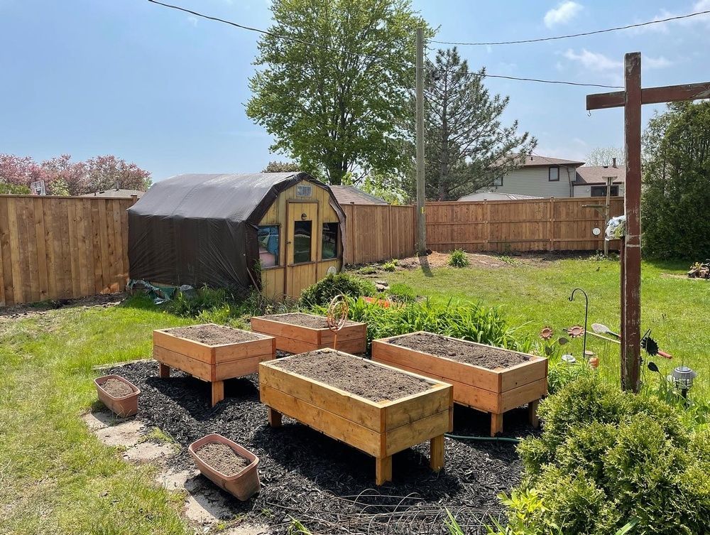 A garden with wooden raised beds and a wooden cross in the backyard.