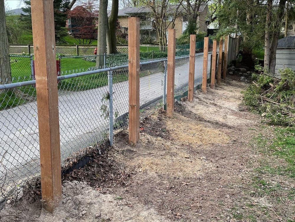 A chain link fence with wooden posts along the side of it.