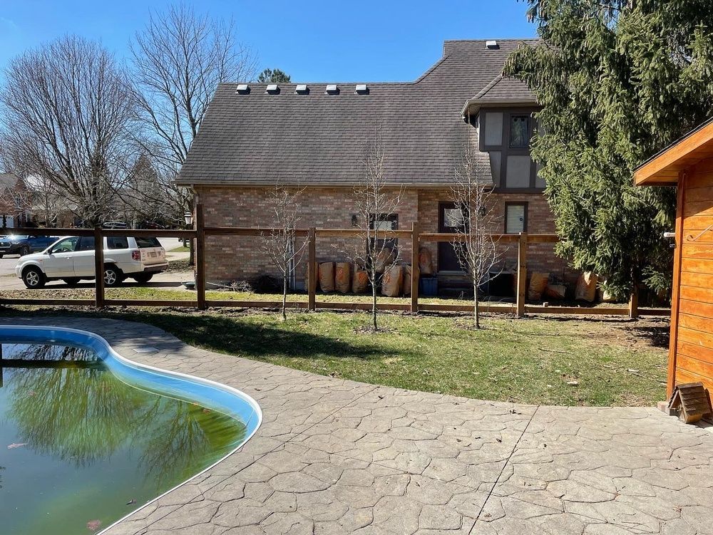 A house with a fence around it and a pool in front of it