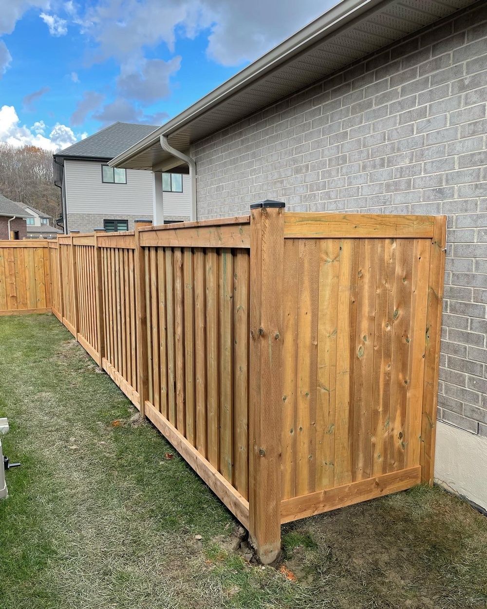A wooden fence is sitting in front of a brick house.