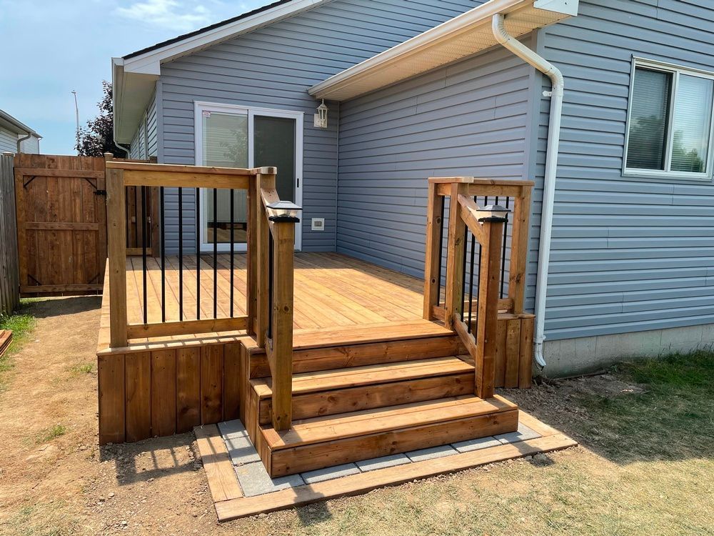A wooden deck with stairs is in front of a house.