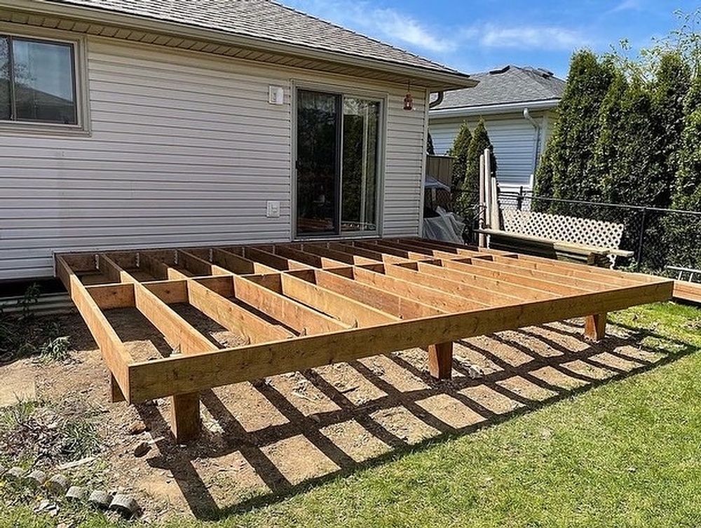 A wooden deck is being built in the backyard of a house.