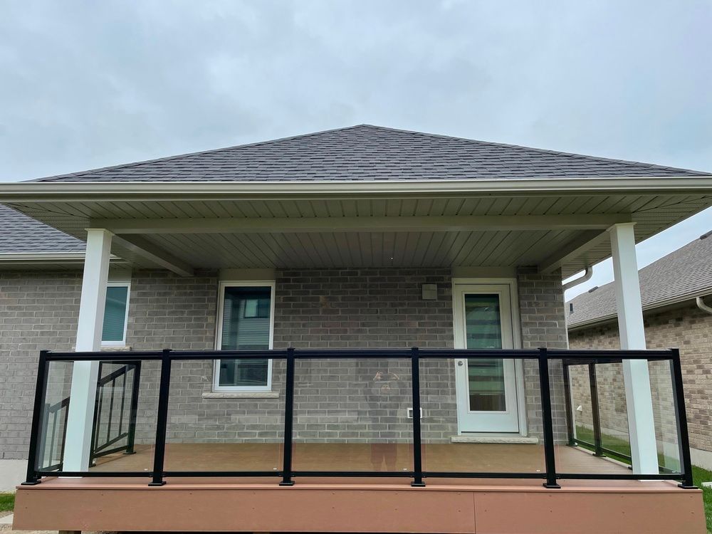 A brick house with a porch and a black railing.