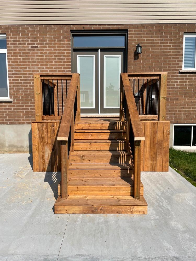 A wooden deck with stairs leading up to the front door of a brick house.