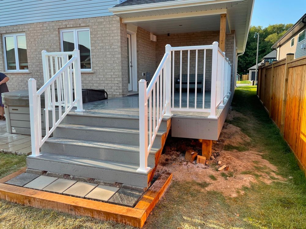 A deck with stairs and a white railing is in the backyard of a house.