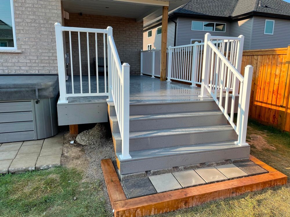 A deck with stairs and a white railing in the backyard of a house.