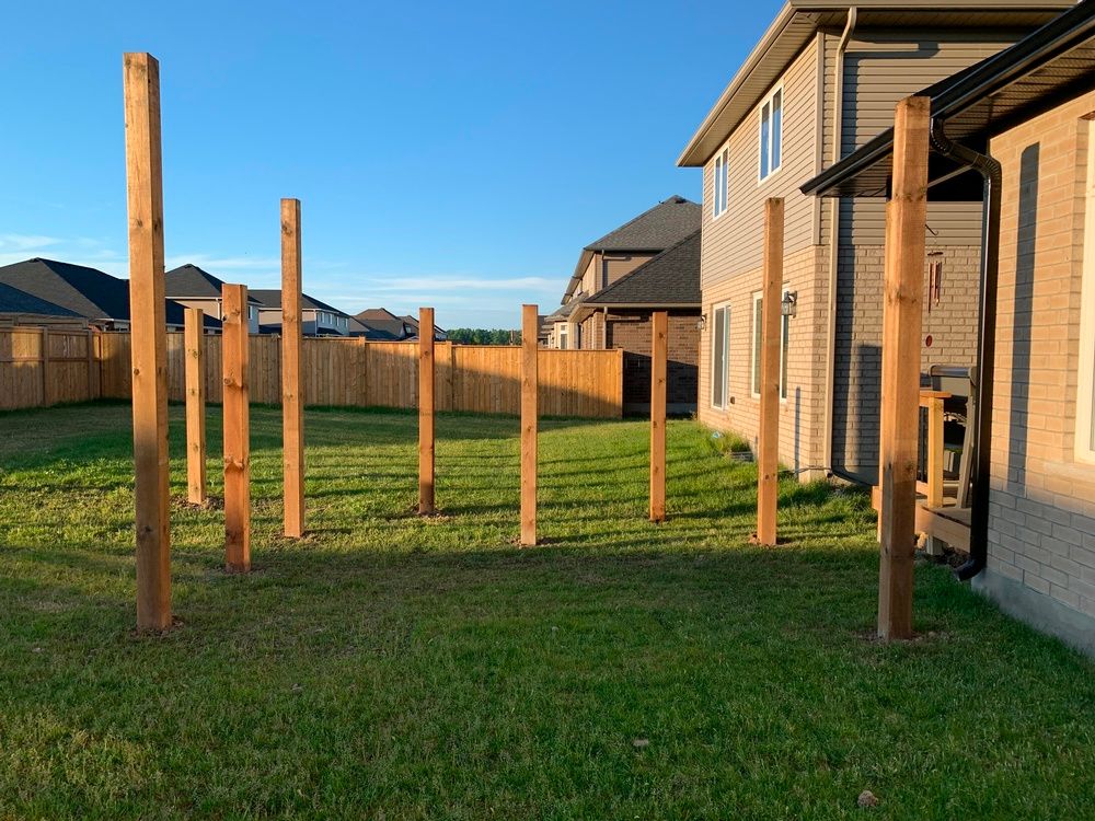 A backyard with a fence and wooden posts in the grass.