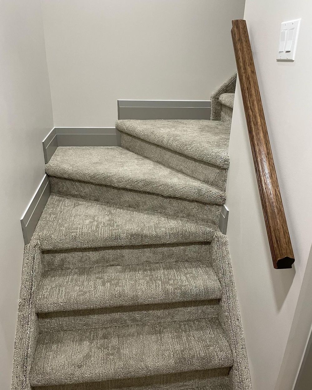 A set of stairs with carpeted steps and a wooden railing.
